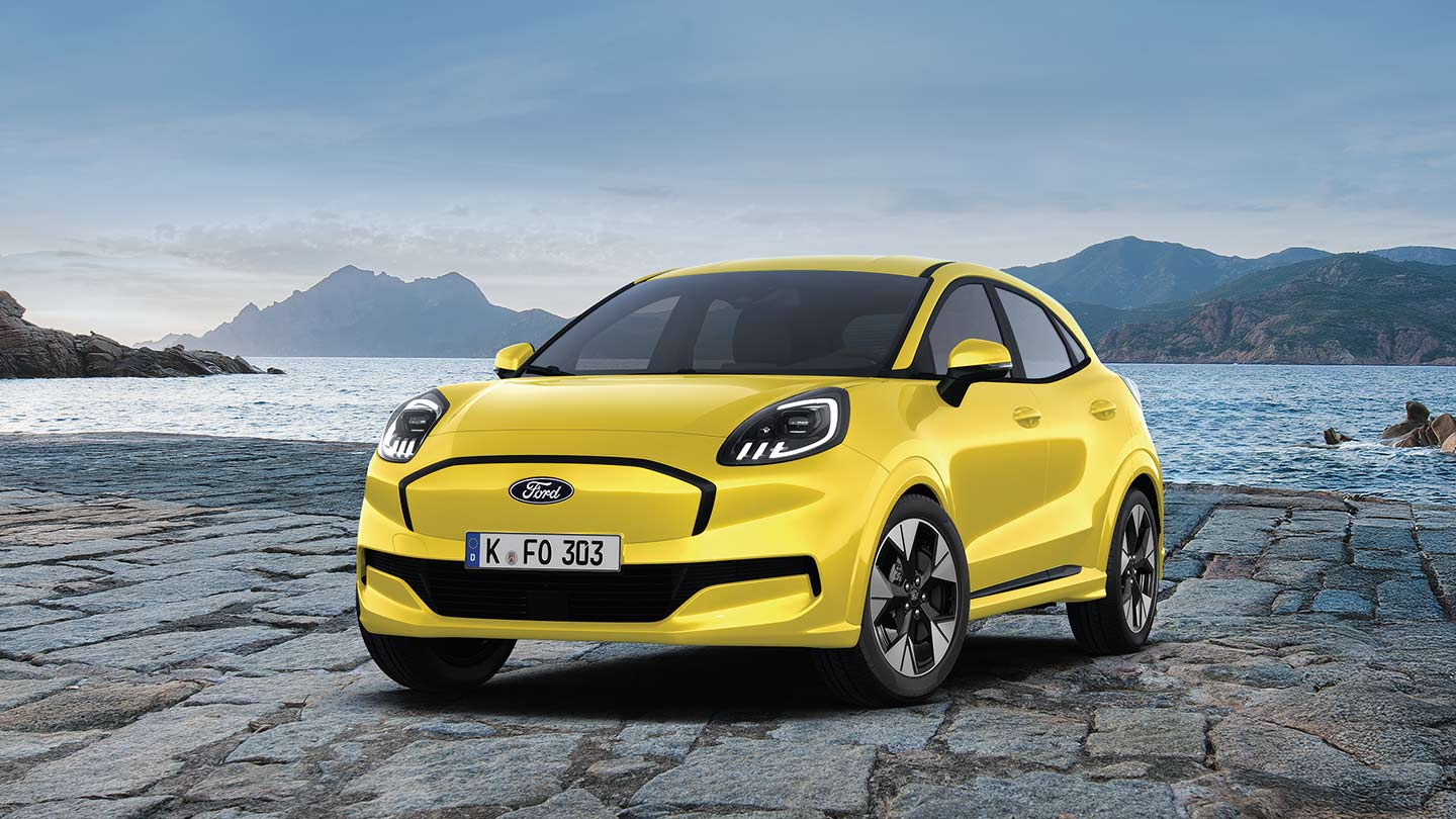Der dynamische und elektrische Ford Puma Gen-E in rot, aufgenommen vor einer malerischen Kulisse mit Bergen und Wasser