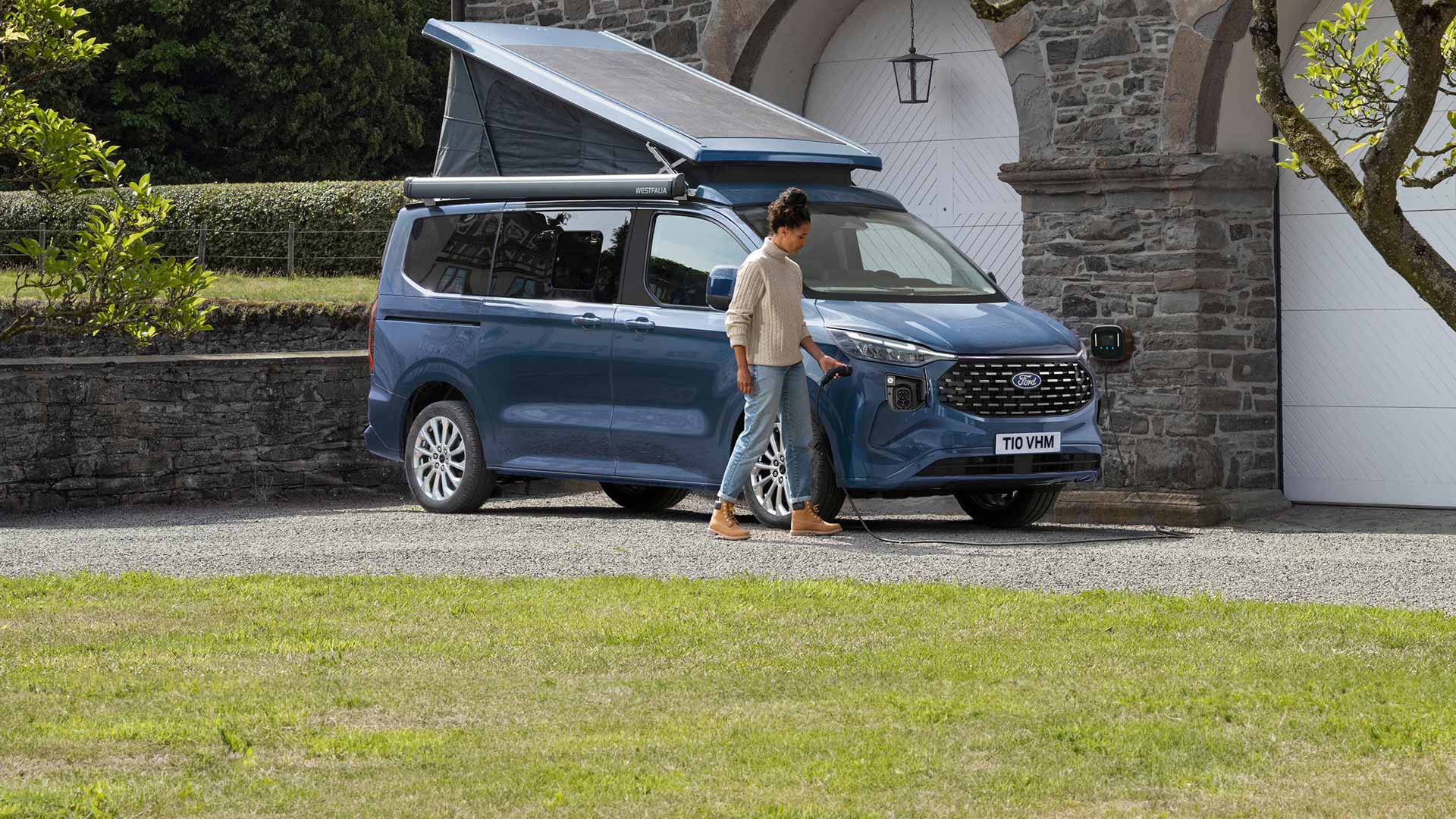 Frau steckt das Kabel zum Aufladen des Ford Nugget PHEV ein.