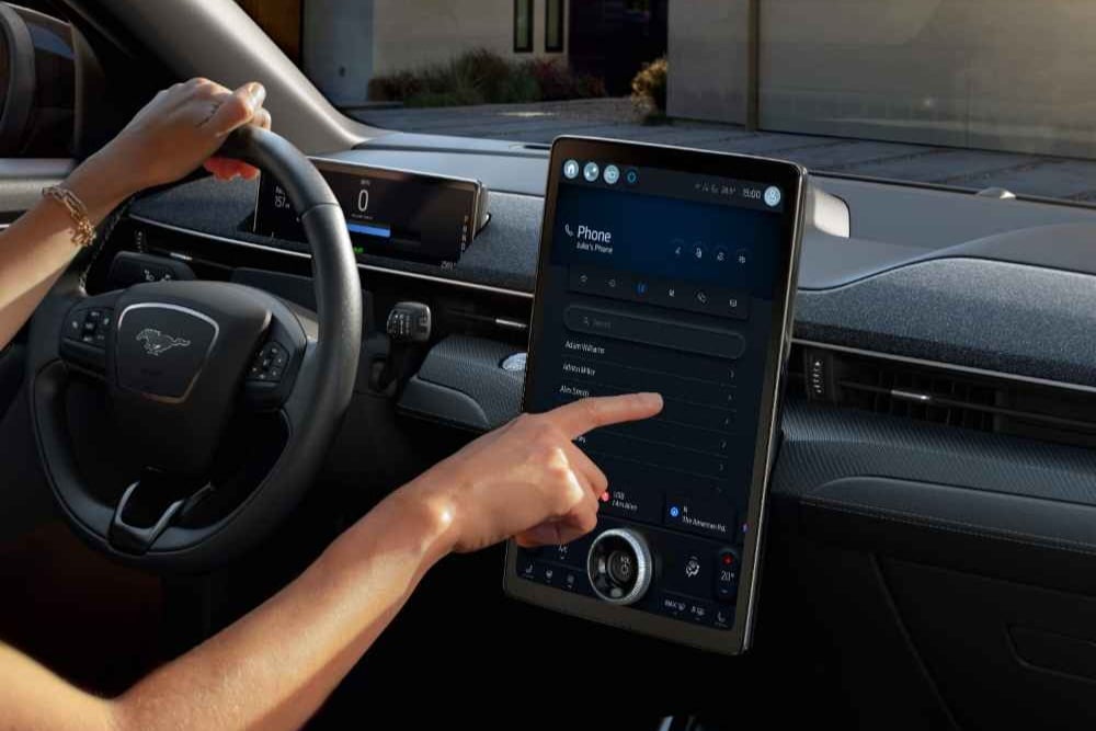 Nahaufnahme des Fahrers eines Ford Mustang Mach-E, der mit dem grossen 15,5" SYNC 4-Touchscreen interagiert