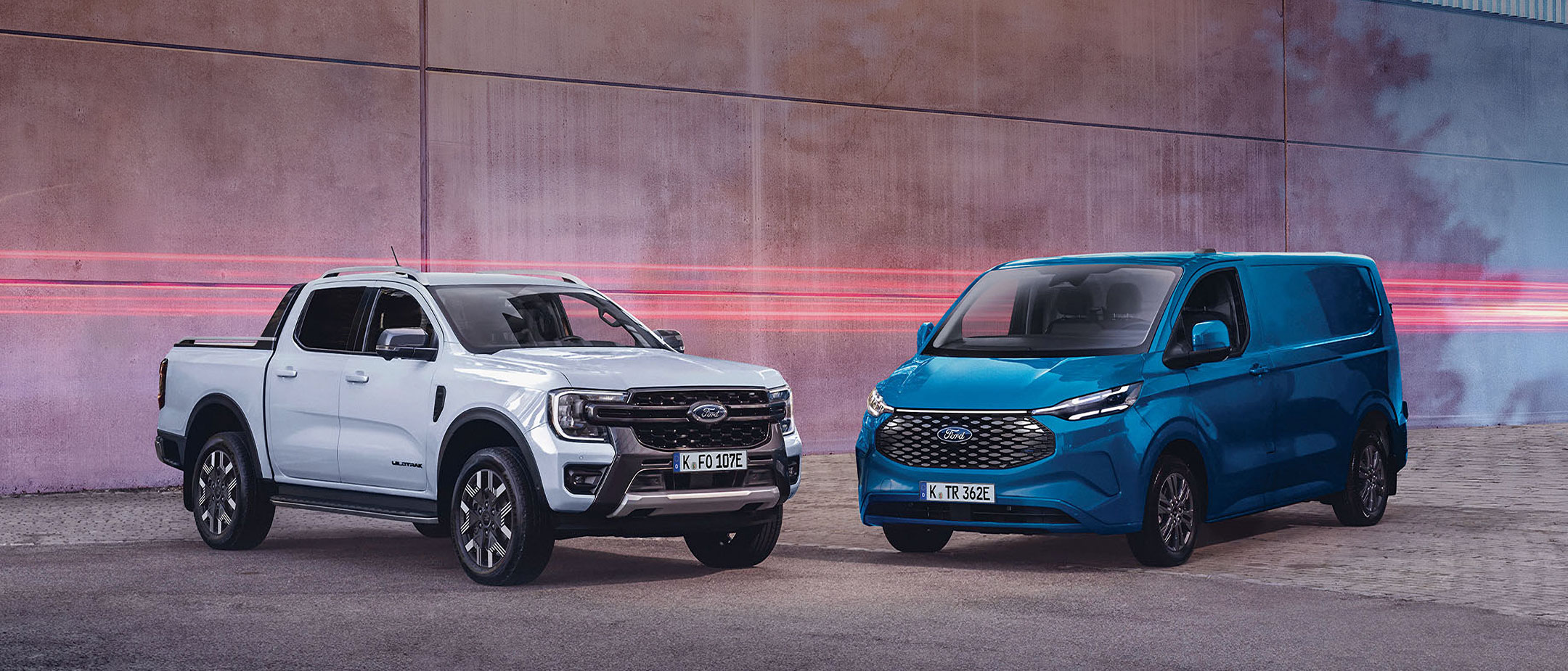 Weisser Ford Ranger und blauer E-Transit Custom nebeneinander geparkt.