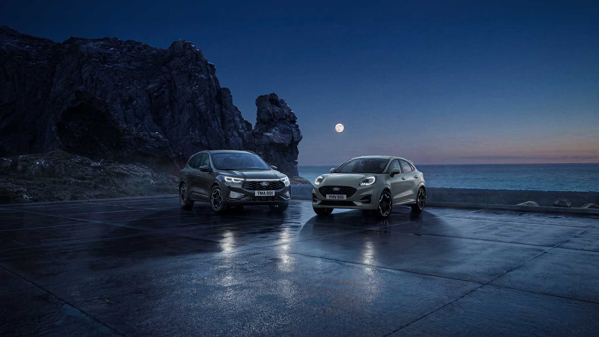Ein Ford Kuga und ein Ford Puma parken bei Nacht an der Küste unter dem Vollmond.
