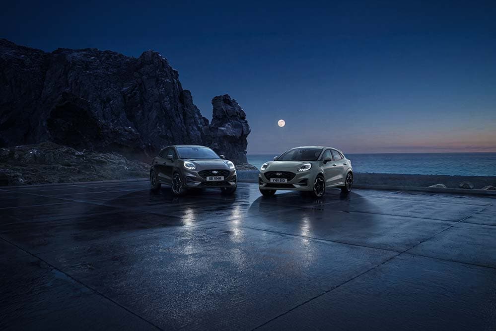 Zwei Ford Puma parken bei Nacht an der Küste unter dem Vollmond.