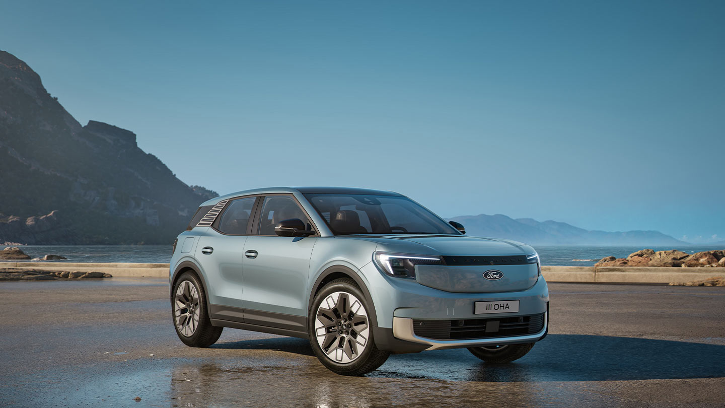 Vorderseitenansicht eines silbernen Ford Explorer, parkiert in der Nähe eines Gewässers, mit Bergen im Hintergrund.