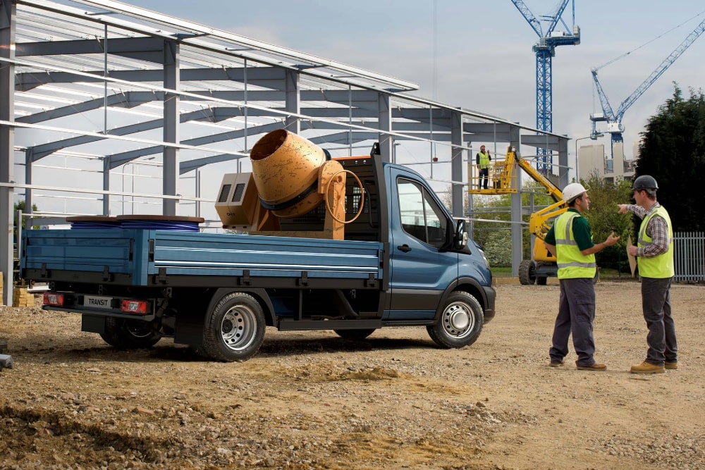 Ford Transit Fahrgestell in Blau. Seitenansicht, beladen auf einer Baustelle
