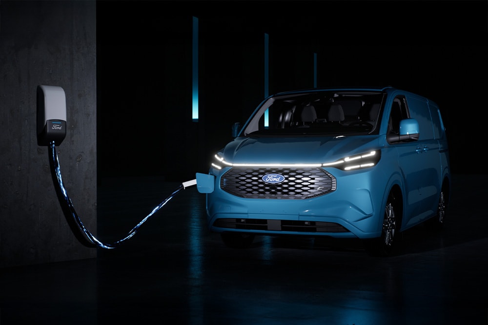 Ein blauer Ford E-Transit Custom wird an einer Ladestation aufgeladen.