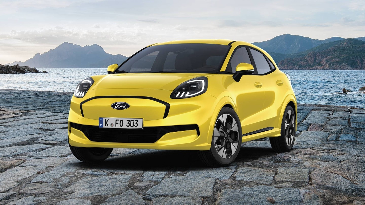 Der dynamische und elektrische Ford Puma Gen-E in rot, aufgenommen vor einer malerischen Kulisse mit Bergen und Wasser