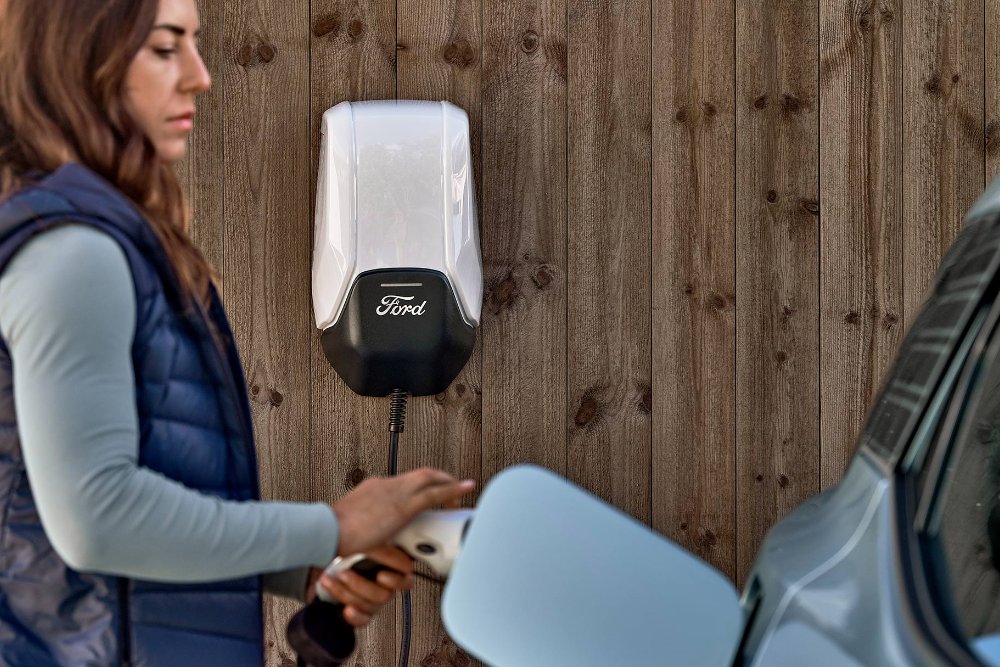 Eine Frau schliesst den neuen Ford Explorer über ein Ladekabel  an die Ford Wallbox an
