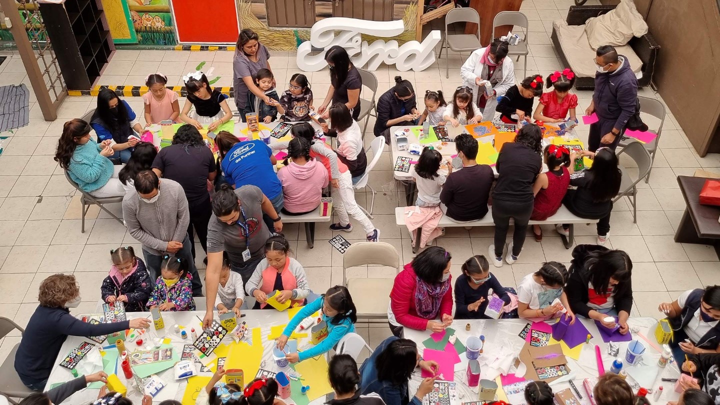 Vogelperspektive auf eine grosse bastelnde Kindergruppe mit Betreuern