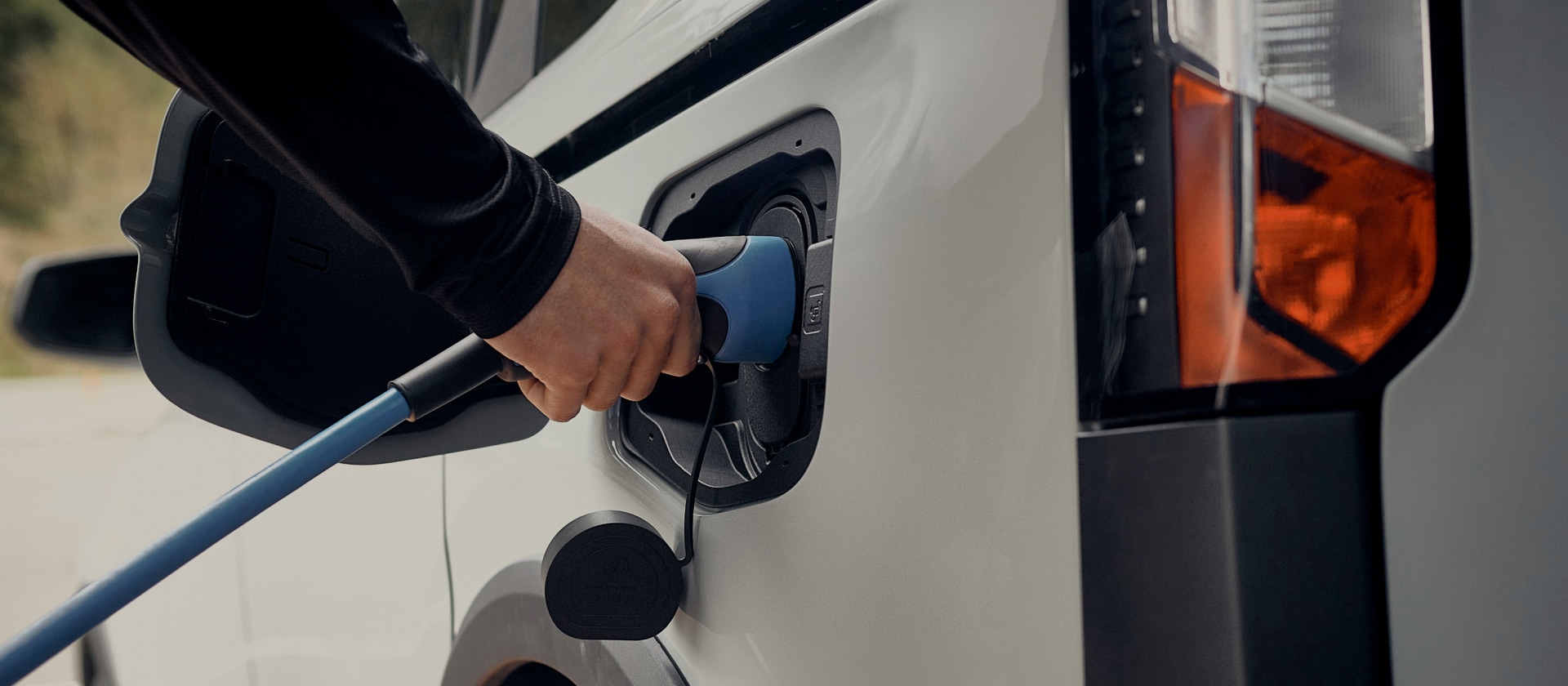 Nahaufnahme eines weissen Ford Elektrofahrzeugs, das an eine EV-Ladestation angeschlossen ist.
