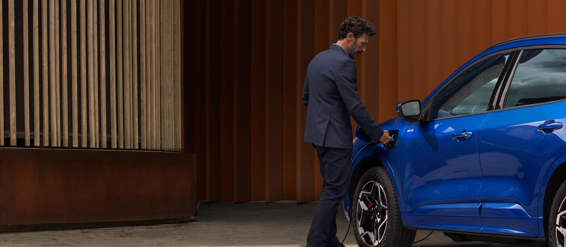 Eine Person schliesst ein Ford Plug-in-Hybrid-Fahrzeug an ein Ladegerät an.