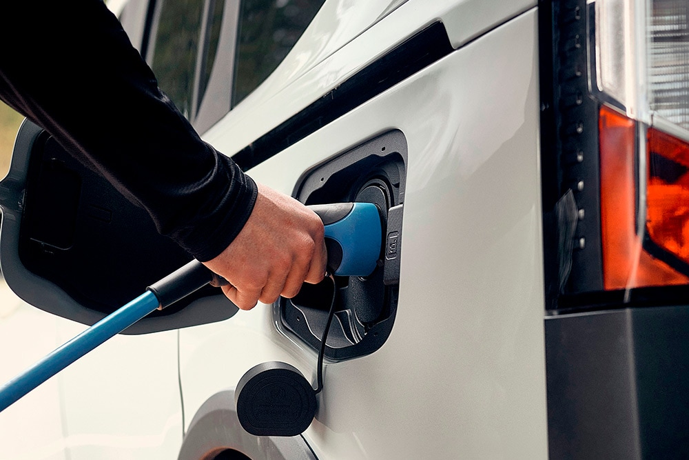 Eine Person schliesst ein Ford Elektrofahrzeug an ein EV-Ladekabel an.