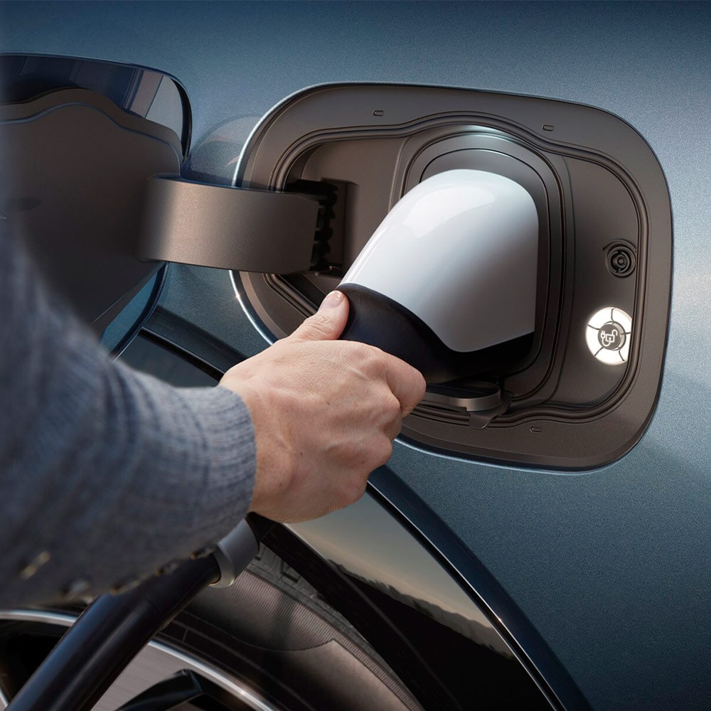 Eine Person schliesst ein Schnellladegerät an ein Ford Elektrofahrzeug an. 