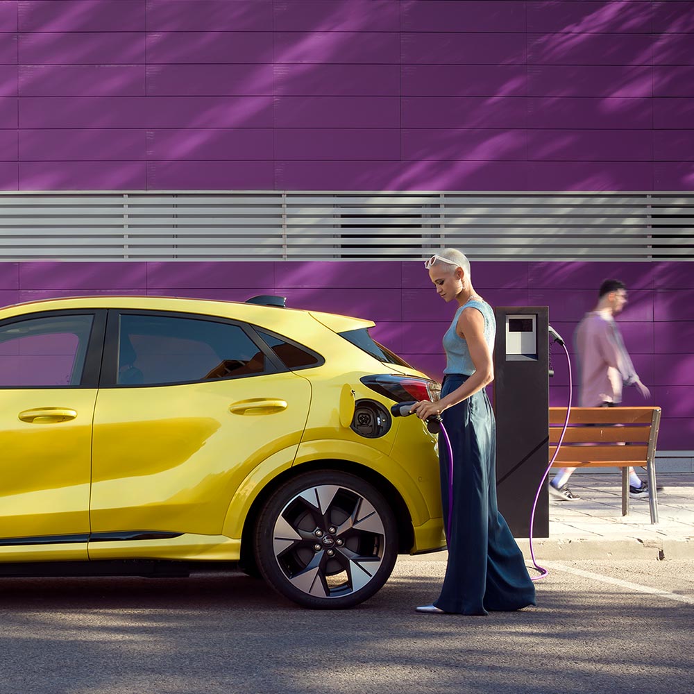 Ein Fahrer schliesst einen gelben Ford Puma Gen-E an eine öffentliche Ladestation an, um das Elektrofahrzeug ganz einfach aufzuladen.
