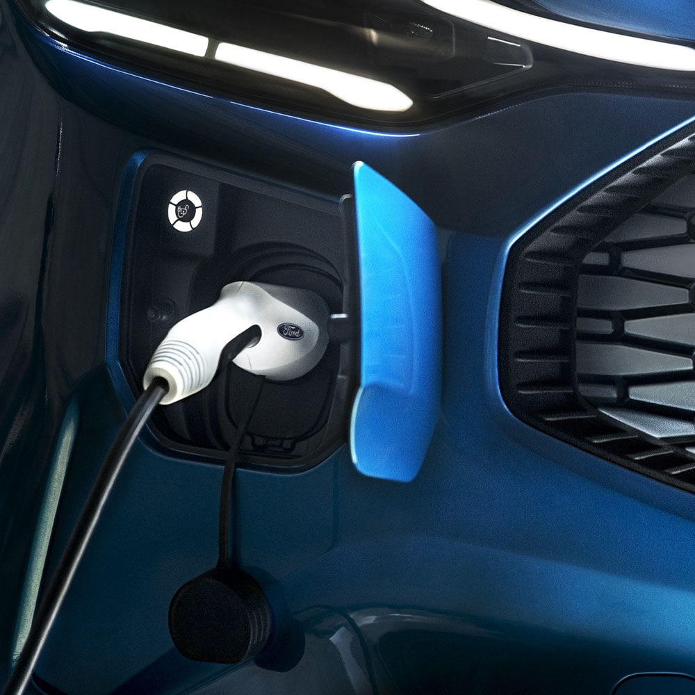 An electric car charging port with an EV charger connected, set against blue Ford vehicle.