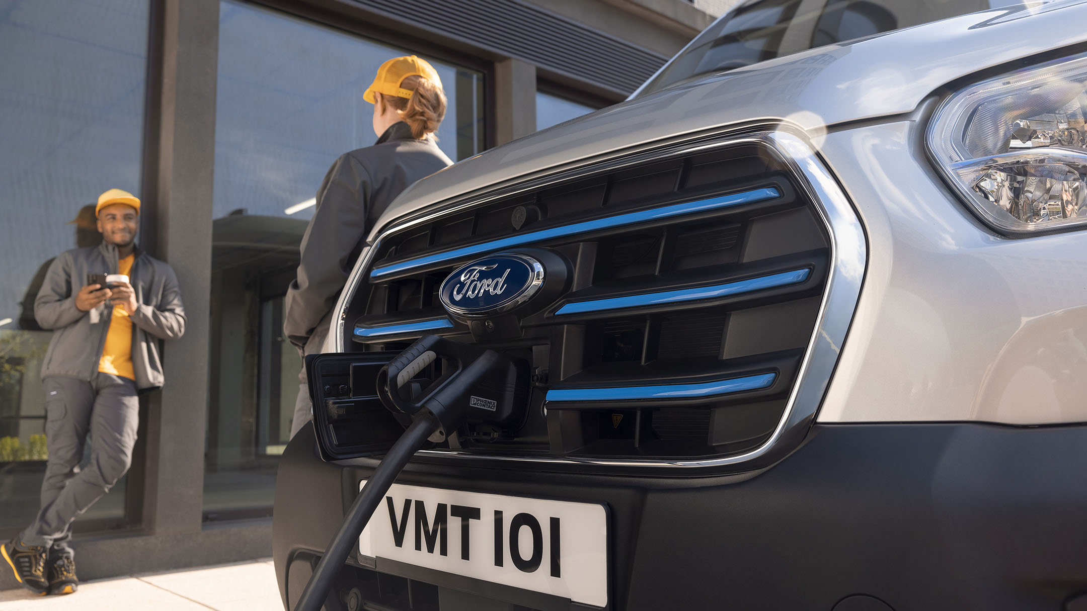 Ford E-Transit im Ladevorgang Detailansicht und zwei Personen im Gespräch