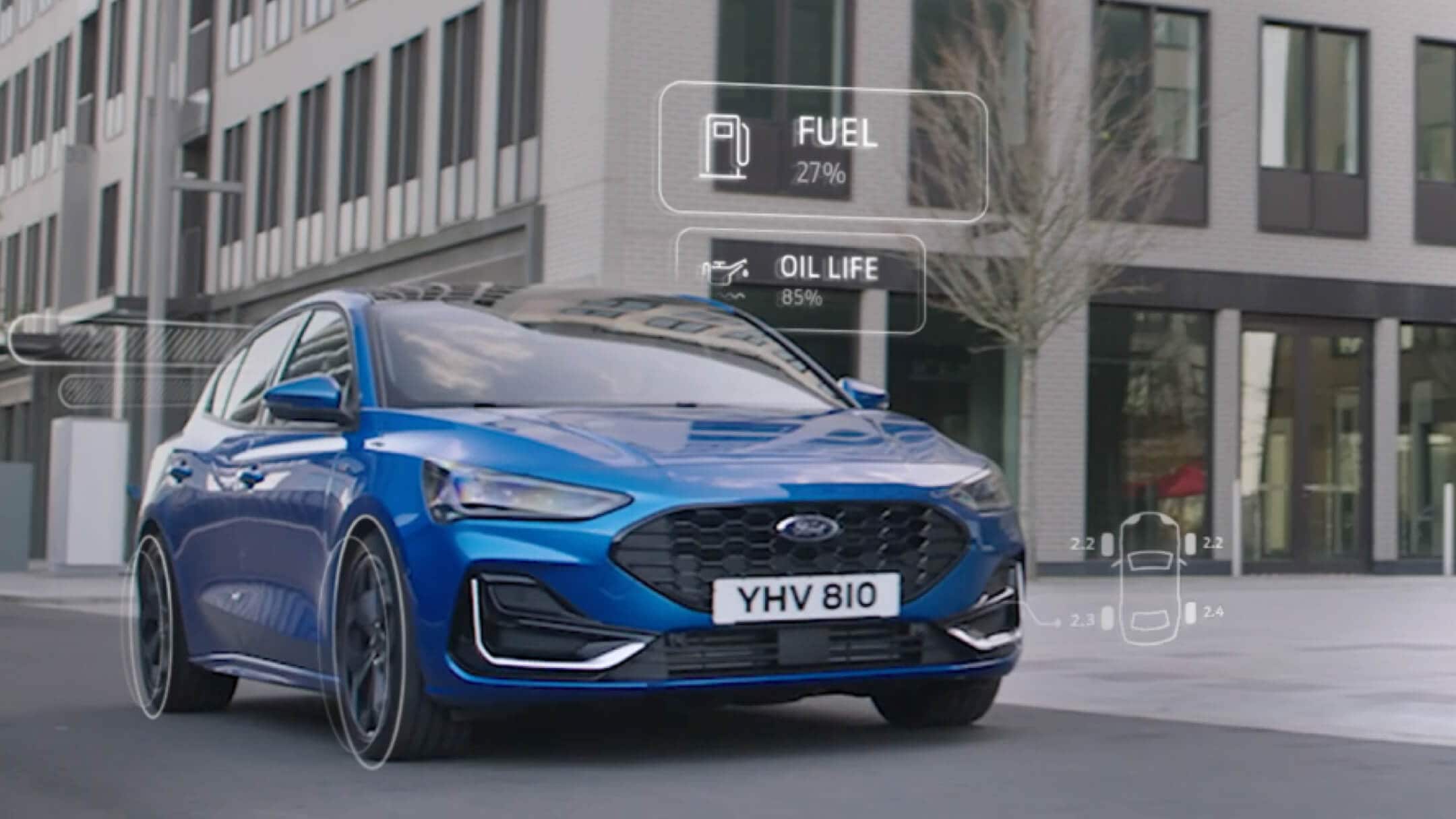 Ford Focus in Blau in der ¾-Frontansicht fährt durch die Stadt mit animierten Anzeigen zum Fahrzeugzustand