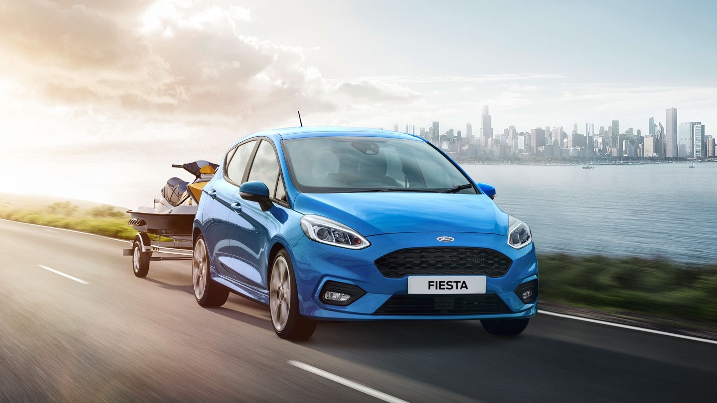 Ford Fiesta ST in Blau. Dreiviertel-Frontansicht mit angehängtem Jetski.