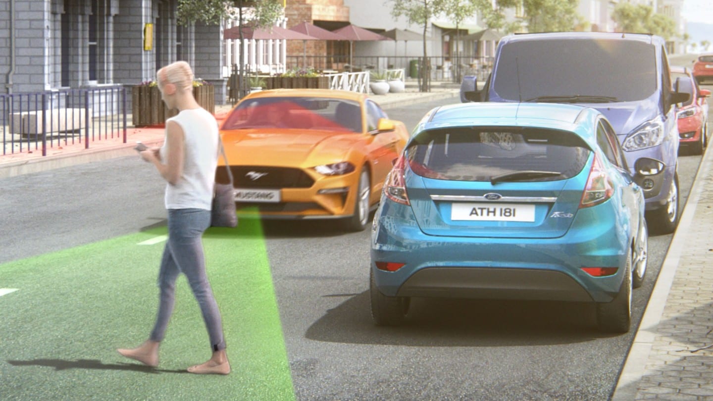Ford Mustang in Orange. Frontalansicht, fahrend über eine Strasse mit Gegenverkehr und visualisierten Pre-Collision-Assist, das einen Fussgänger erkennt