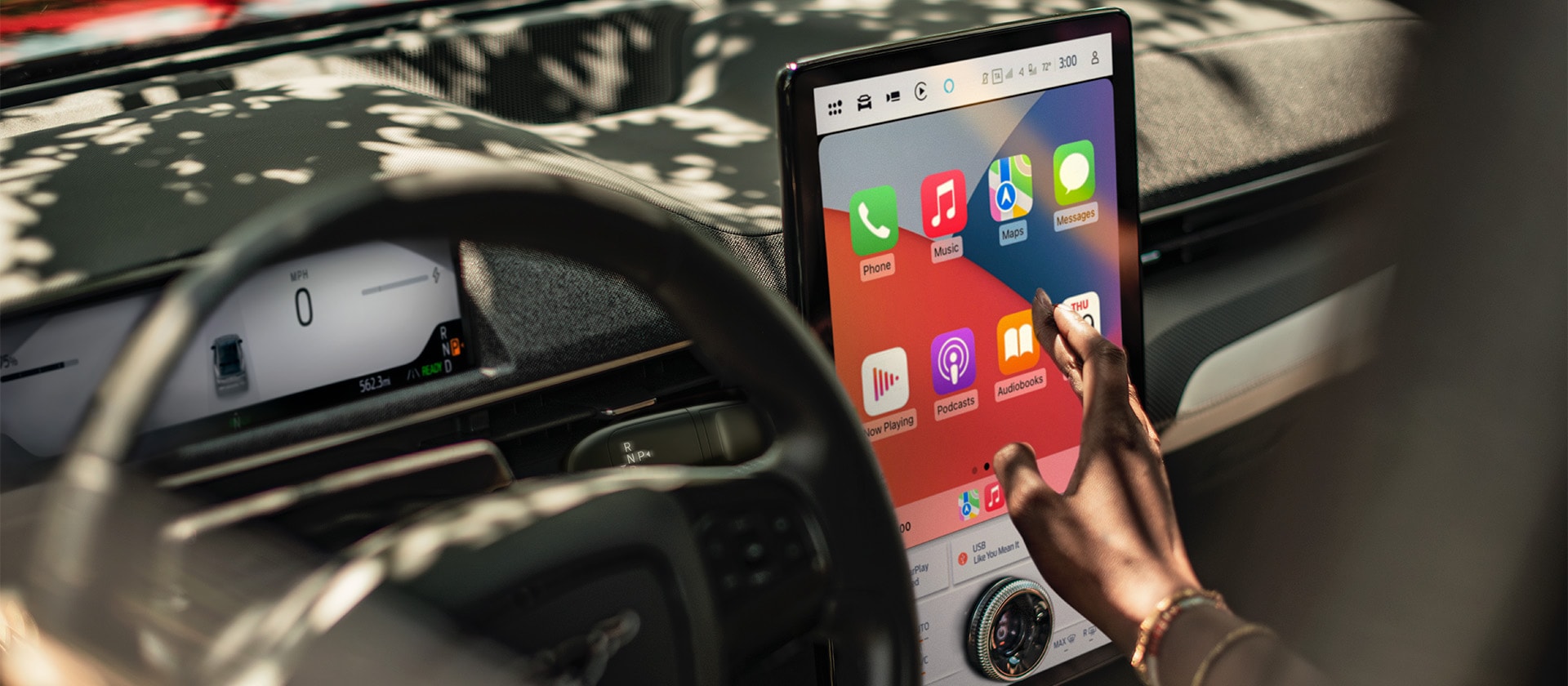 Fahrer eines Ford Mustang Mach-E, der mit dem 15,5-Zoll-SYNC-4-Touchscreen interagiert, auf dem Apple CarPlay angezeigt wird. 