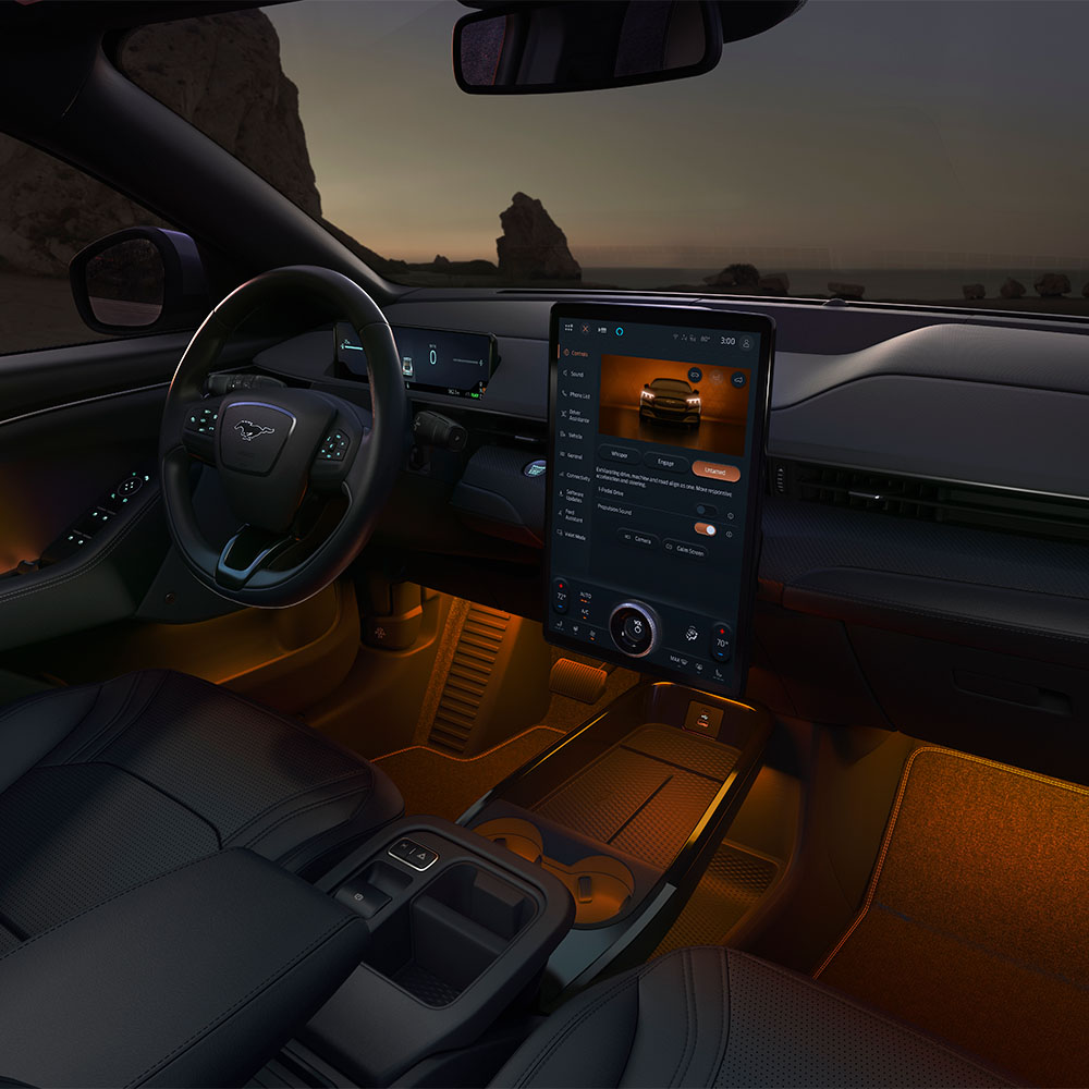 Ford Mustang Mach-E bei Nacht, mit dem 15,5-Zoll-SYNC-4-Touchscreen und auf Orange eingestellter LED-Ambientebeleuchtung.