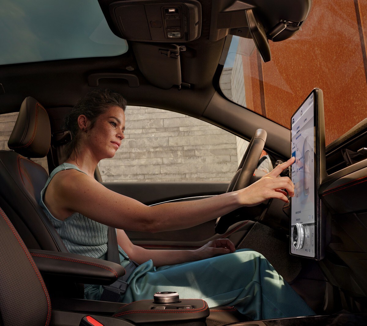 Ford Mustang Mach-E. Innenraumansicht. Fahrerin benutzt Ford SYNC 4 Touchscreen