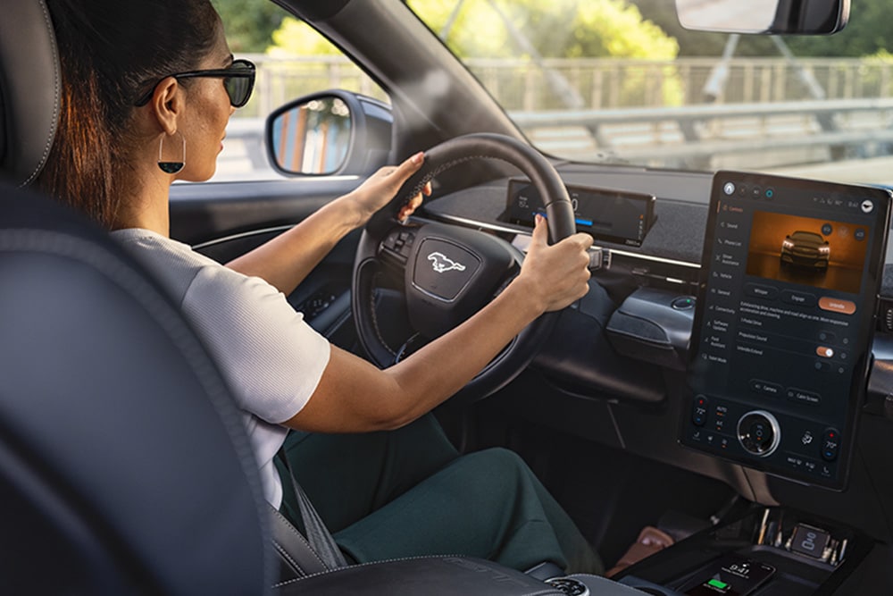 Ford Mustang Mach-E bei Nacht, mit dem 15,5-Zoll-SYNC-4-Touchscreen und auf Orange eingestellter LED-Ambientebeleuchtung.