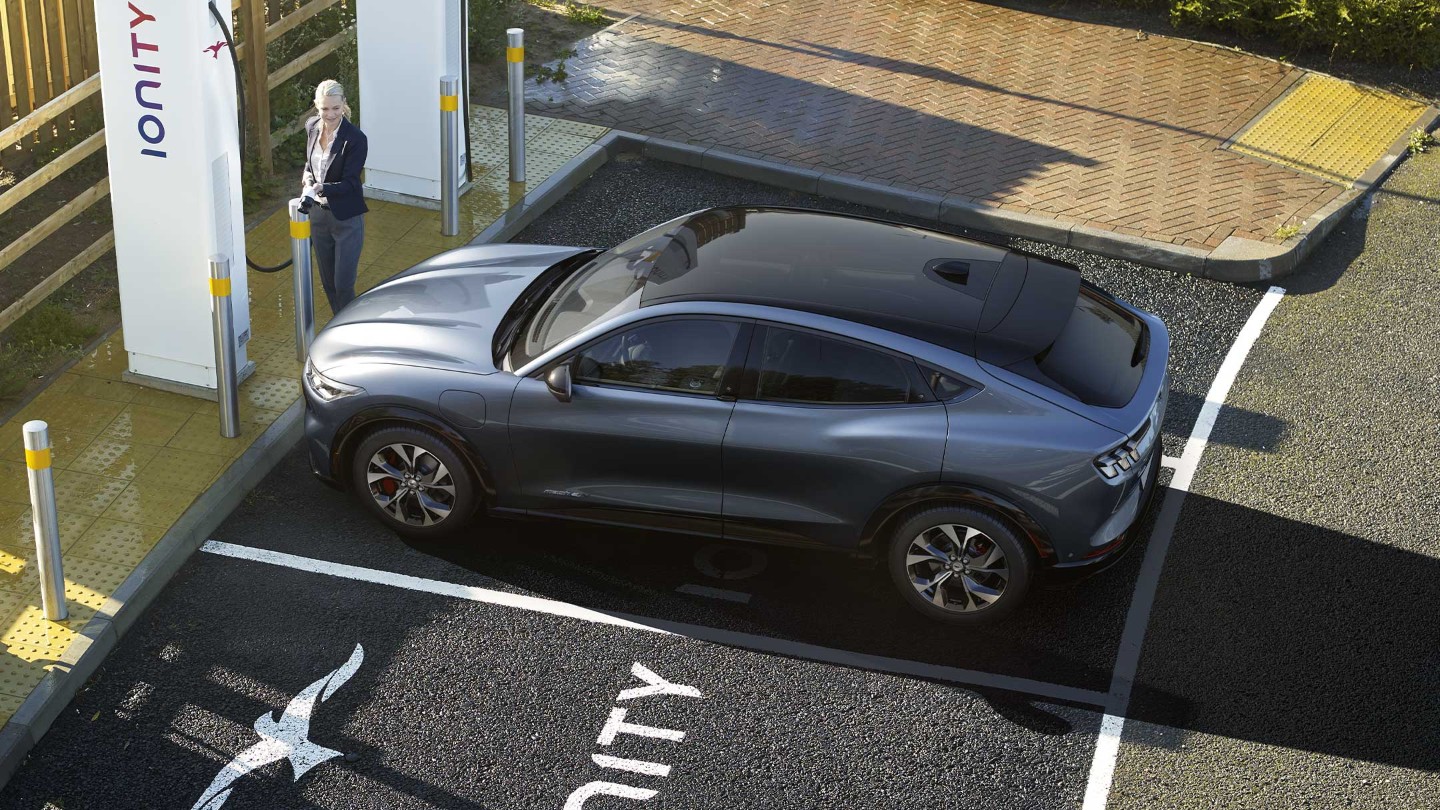 Eine Frau lädt einen brandneuen Ford Mustang Mach-E an einer IONITY-Ladestation auf