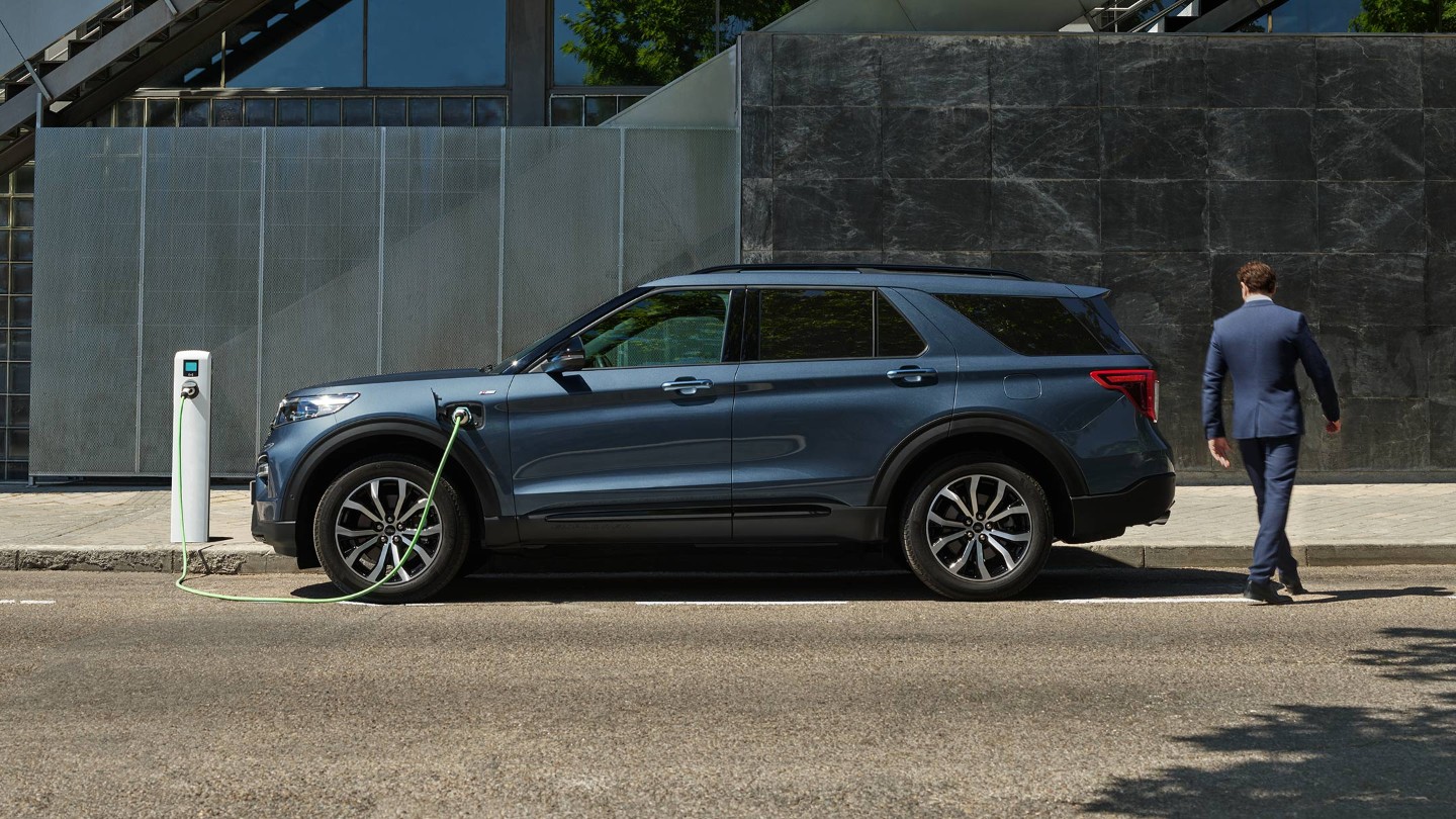 Ford Explorer Plug-in-Hybrid in Blau. Seitenansicht. Ladevorgang an einer Ladestation.