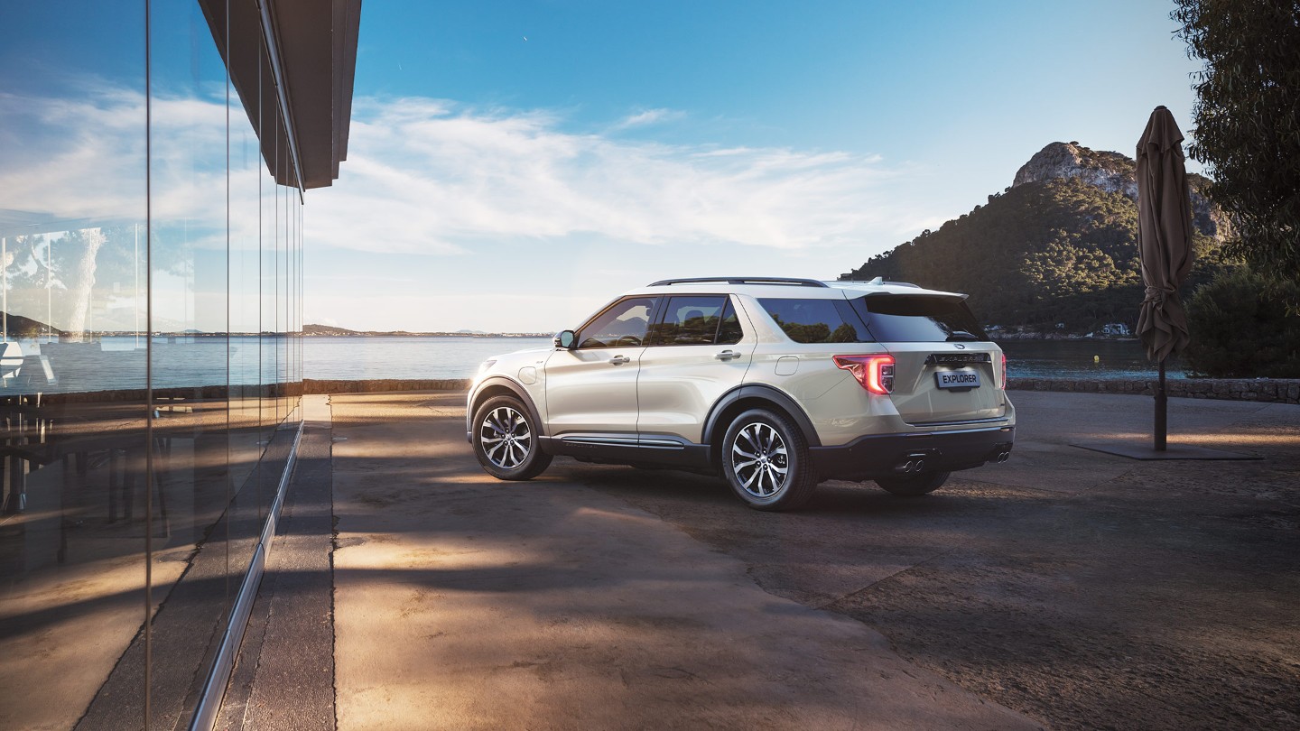 Ford Explorer Plug-In Hybrid in Weiss. Dreiviertel-Heckansicht. Am Strand parkend