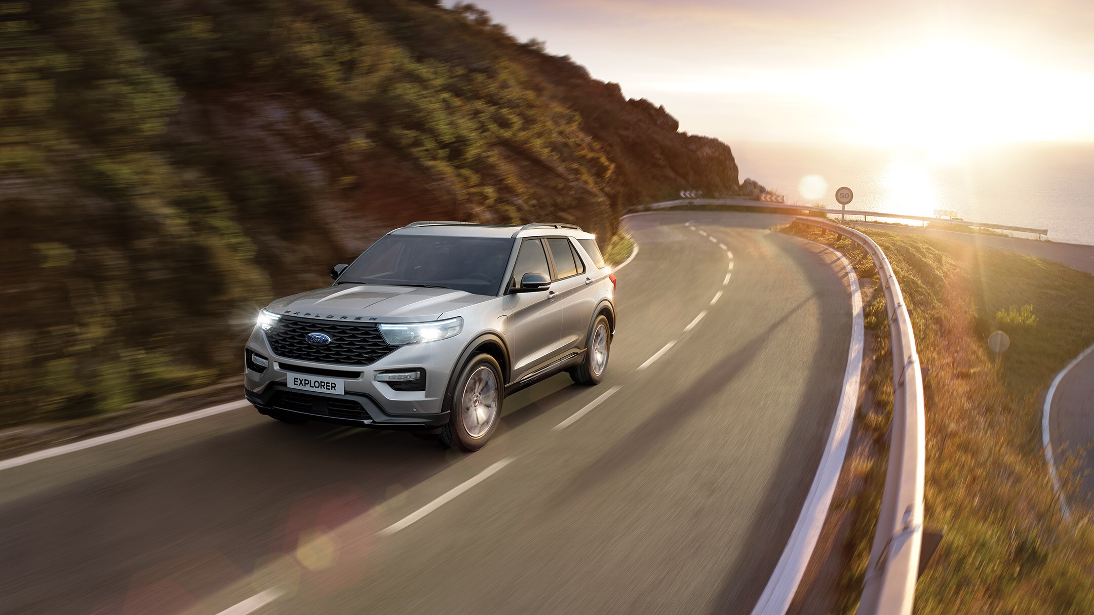 Ford Explorer Plug-In Hybrid in Silber. Fahrszene auf einer kurvigen Landstrasse