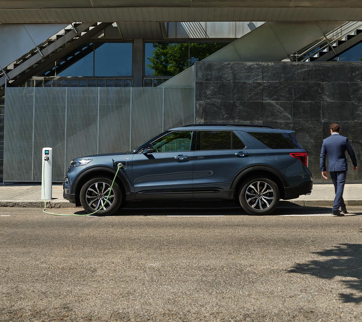 Ford Explorer Plug-In Hybrid in Blau. Seitenansicht. An einer Ladestation parkend