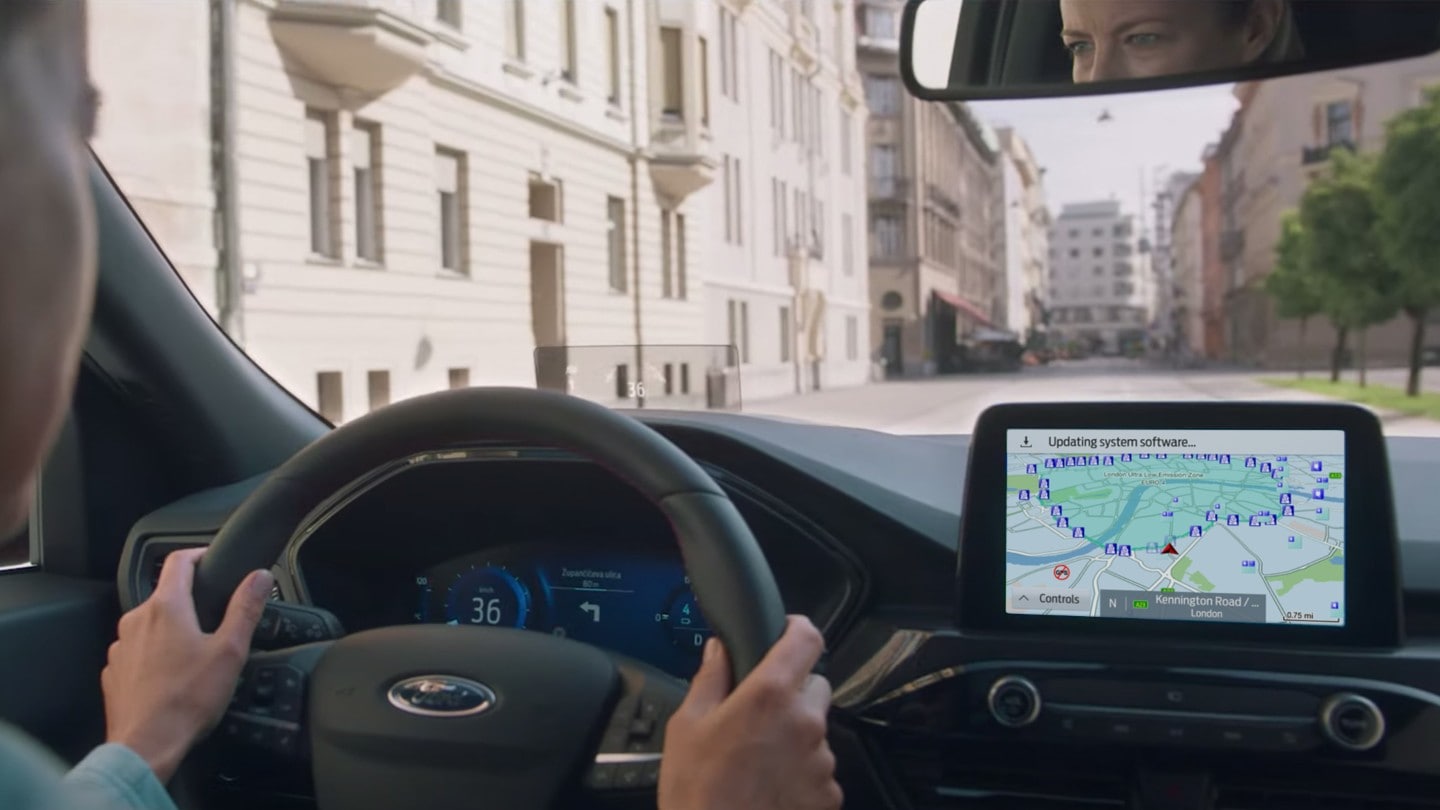 Ford Kuga Innenraumansicht. Blick durch die Windschutzscheibe, Hände des Fahrers am Steuer und Ford SYNC 3 Bildschirm