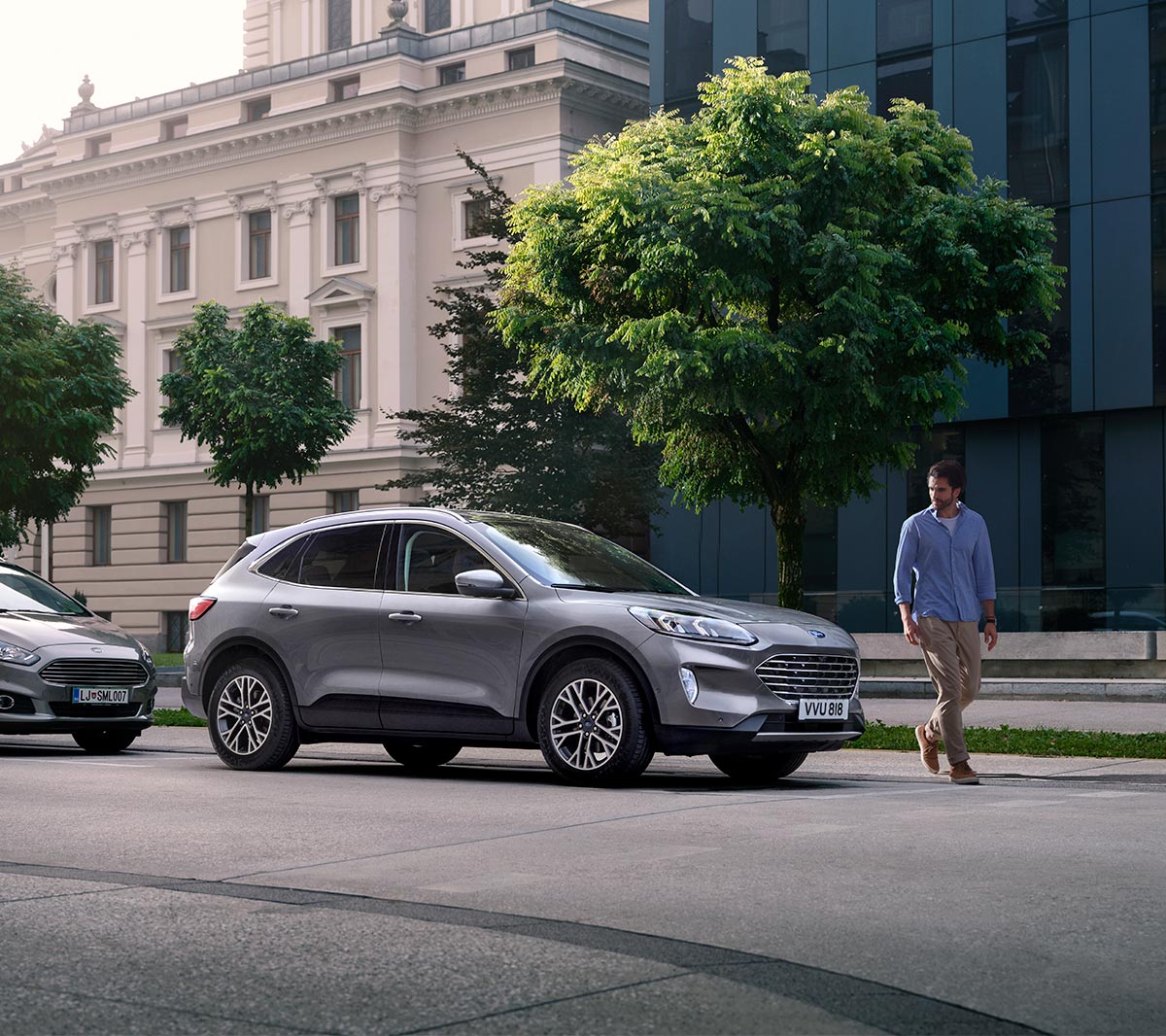 Ford Kuga in Silber. 3/4-Frontansicht, vor einem Altbaugebäude parkend