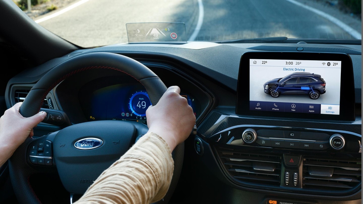 Ford Kuga. Innenrau-Detailansicht Lenkrad und Mittelkonsole mit Touchscreen. Hände des Fahrers am Lenkrad