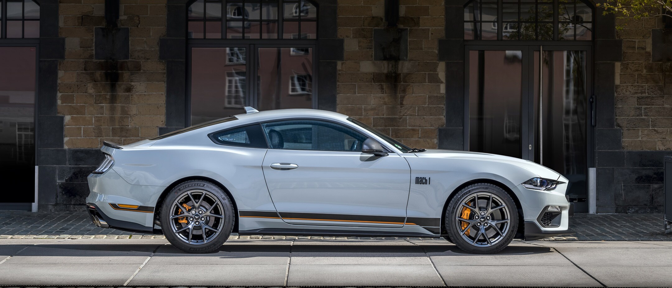 Ford Mustang Mach 1 in Weiss. Seitenansicht, vor einem modernen Gebäude stehend