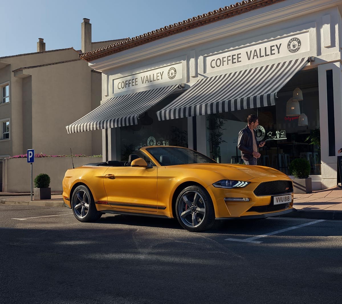 Ford Mustang California in Orange. Dreiviertel-Frontansicht, vor einem Geschäft parkend.