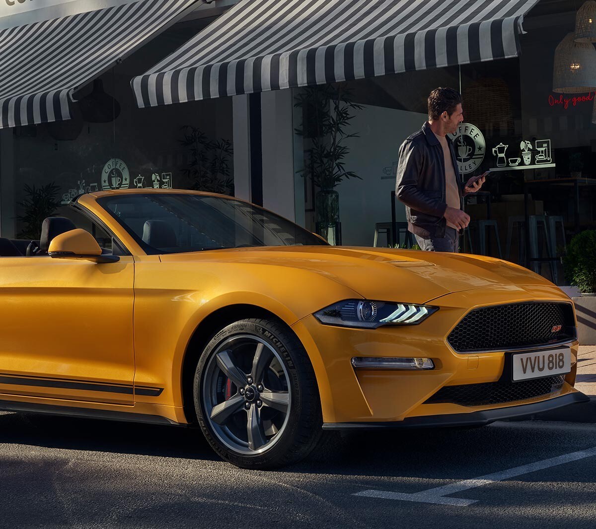 Ford Mustang California in Orange. Dreiviertel-Frontansicht, vor einem Geschäft parkend.