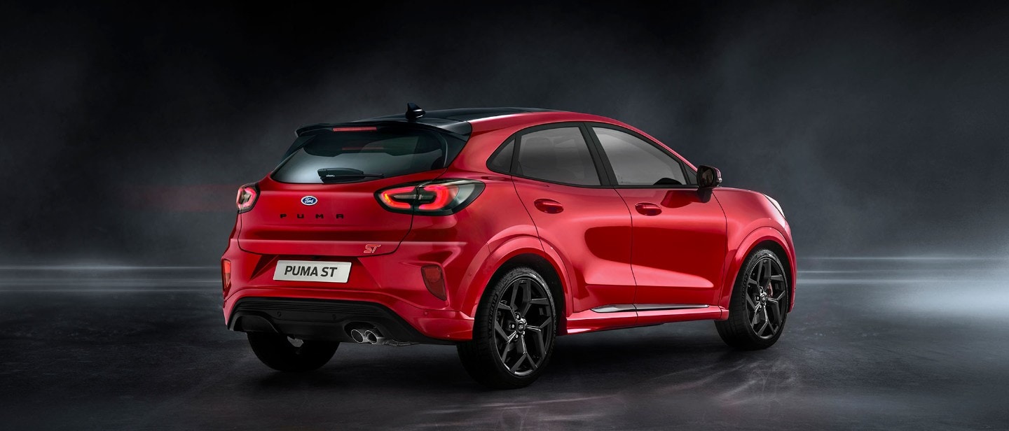 Ford Puma ST in Rot. ¾-Heckansicht stehend in einem dunklen Showroom 