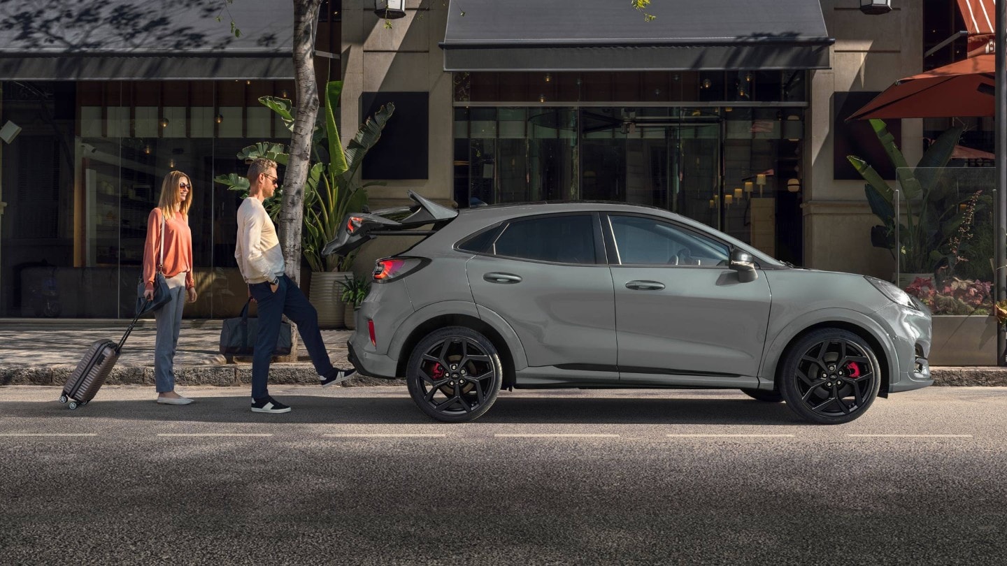 Ford Puma ST in Grau. Nahe Seitenansicht, ein Mann öffnet die sensorgesteuerte Heckklappe per Fussbewegung