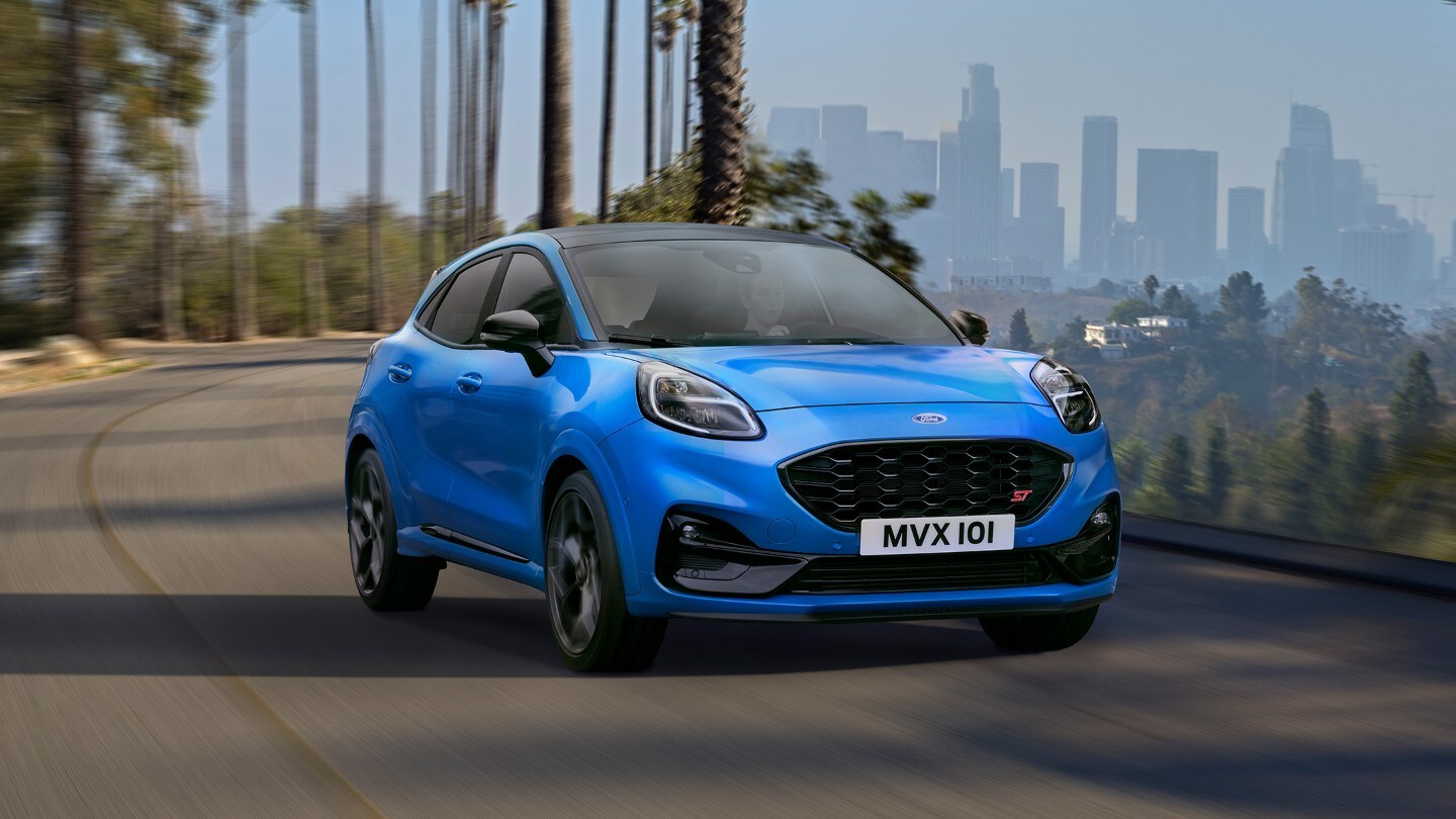 Blauer Ford Puma ST Powershift in ¾-Frontansicht auf einer kurvigen Strasse fahrend