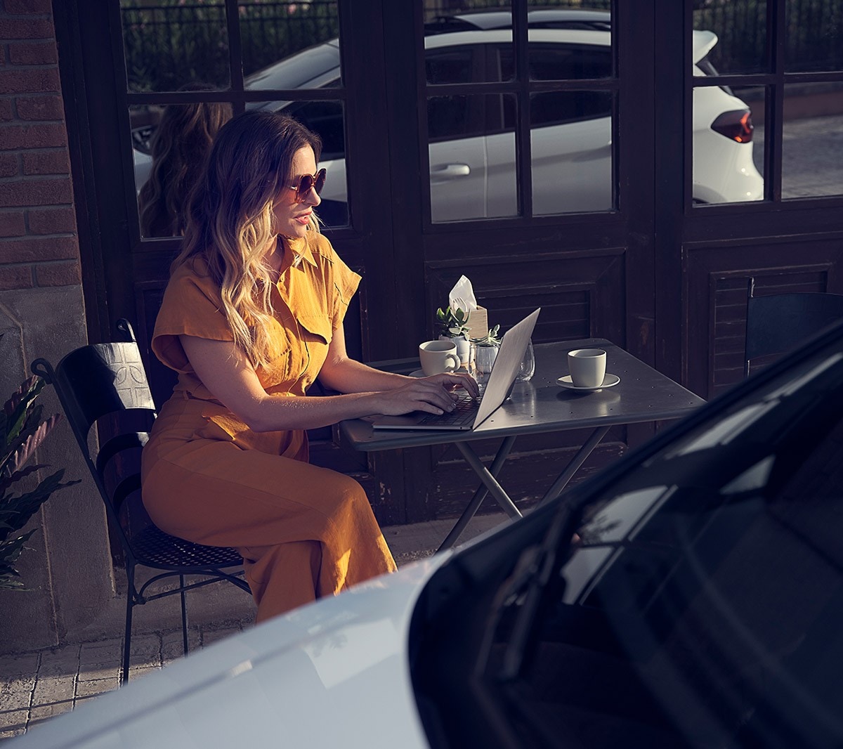 Ford Fiesta in Weiss. Detailansicht der Front, vor einem Café parkend mit Frau im Hintergrund.
