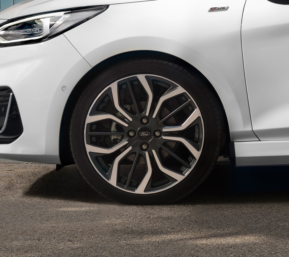 Ford Fiesta in Weiss. Seitenansicht der Front, vor einem Haus parkend mit Frau im Vordergrund.