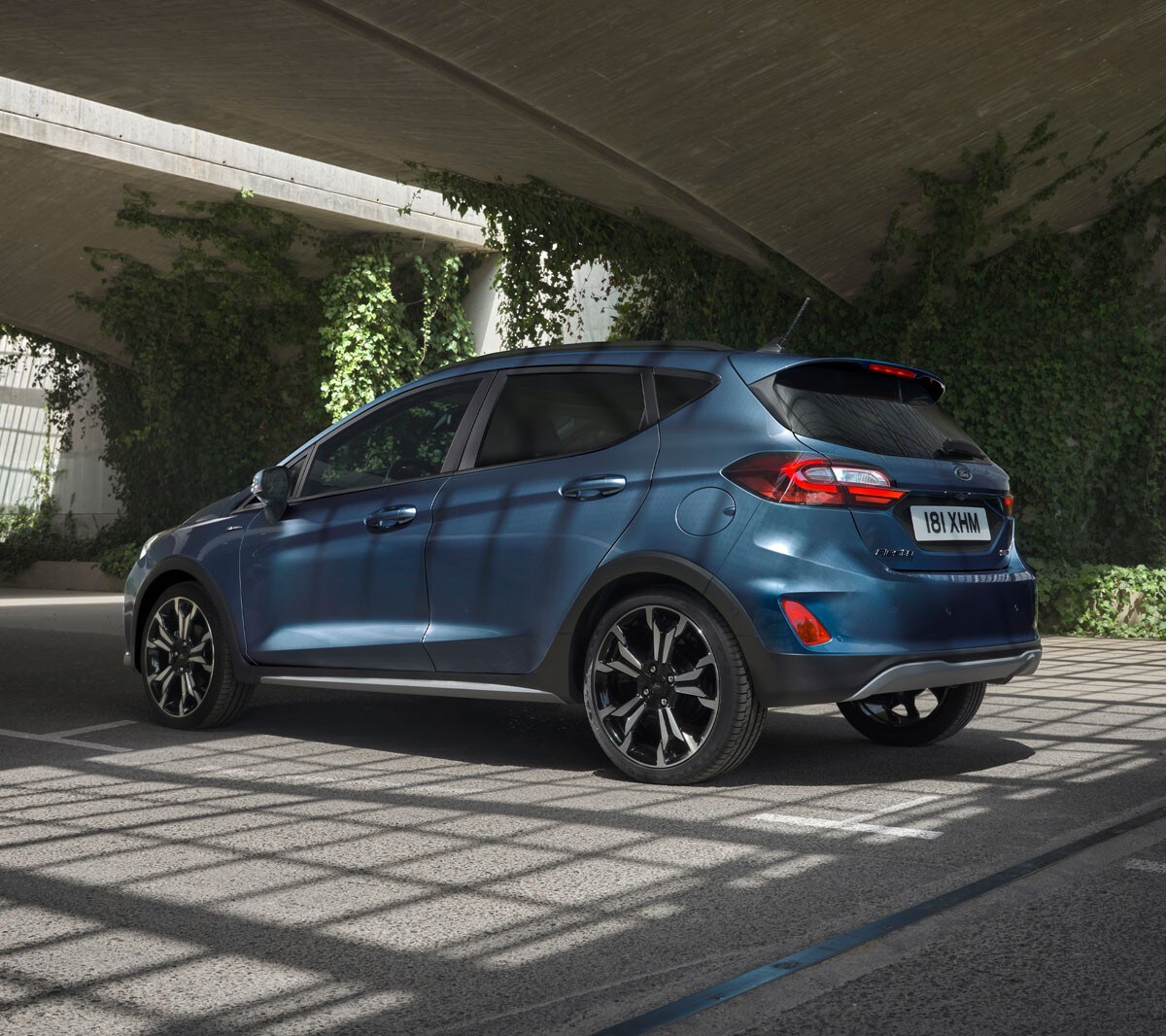 Ford Fiesta in Blau. Dreiviertel-Heckansicht, unter Brücken fahrend.