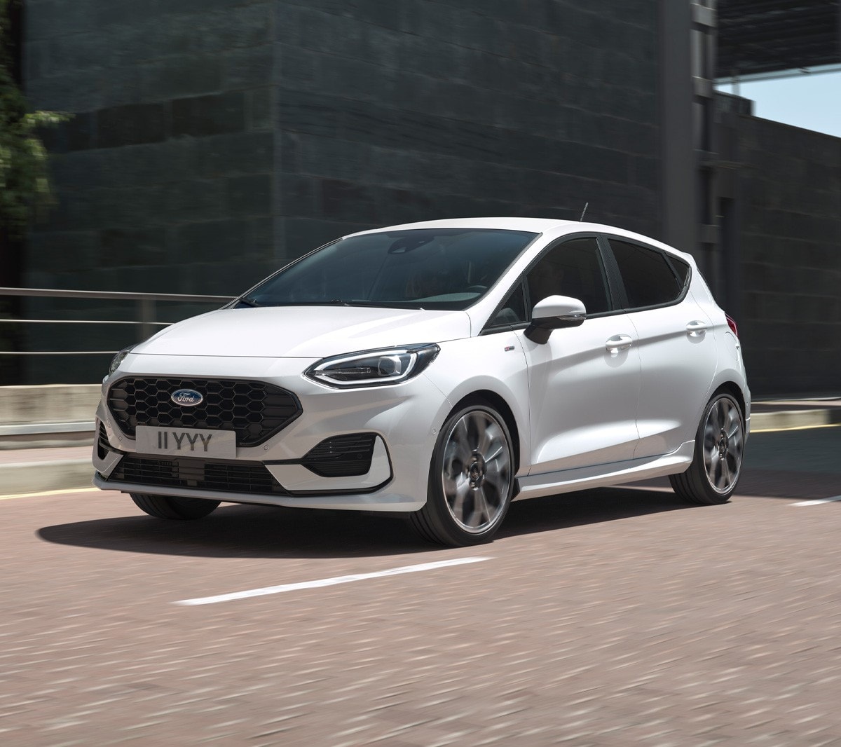 Ford Fiesta in Weiss. Dreiviertel-Frontansicht in einer Stadt fahrend mit modernen Gebäuden im Hintergrund.