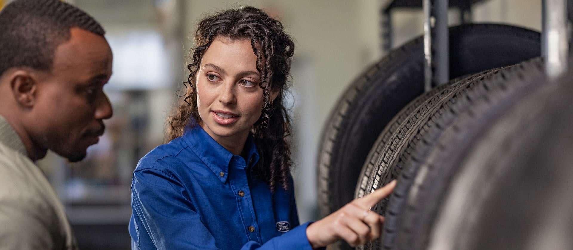 Eine Ford Reparaturspezialistin hilft einem Kunden mit neuen Fiesta-Autoreifen.