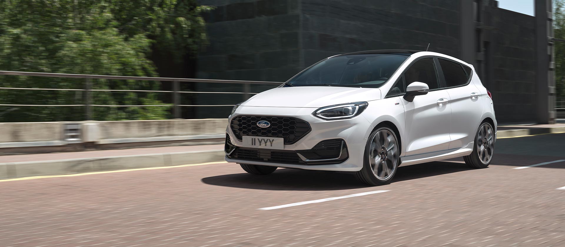 Weisser Ford Fiesta fährt in einer Stadt.