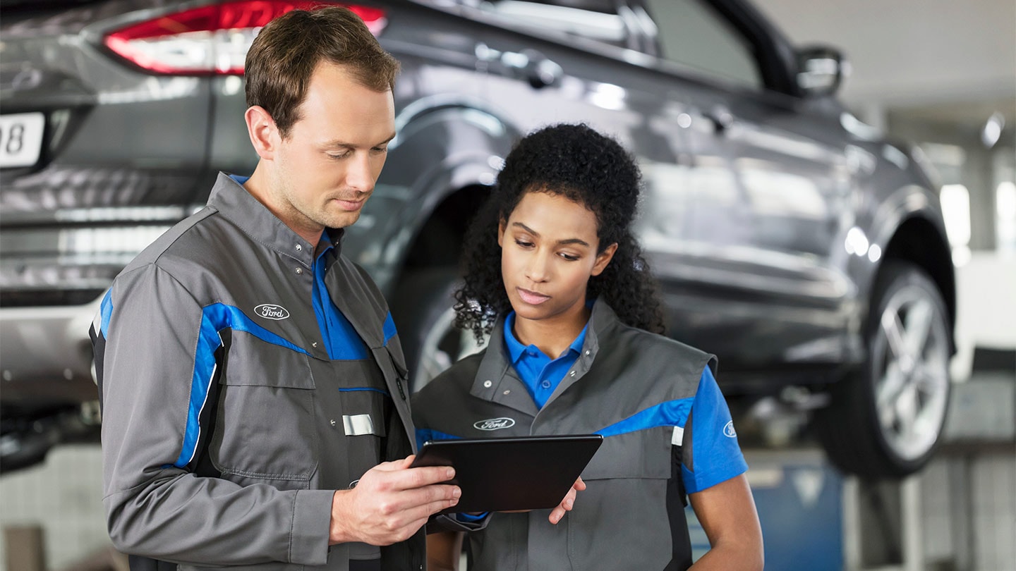 Zwei Ford Reparaturspezialisten überprüfen ihr Online-Service-Buchungssystem am Telefon.