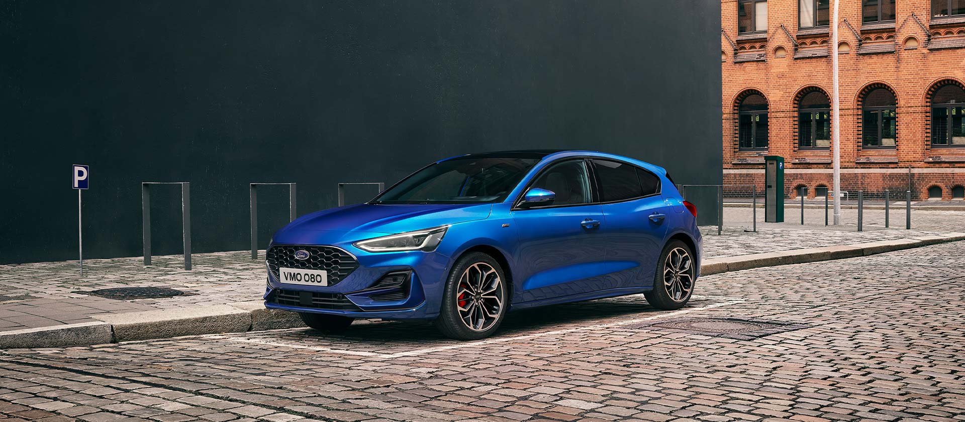 Ein blauer Ford Focus Schrägheck steht auf einer Kopfsteinpflasterstrasse in einer städtischen Umgebung.