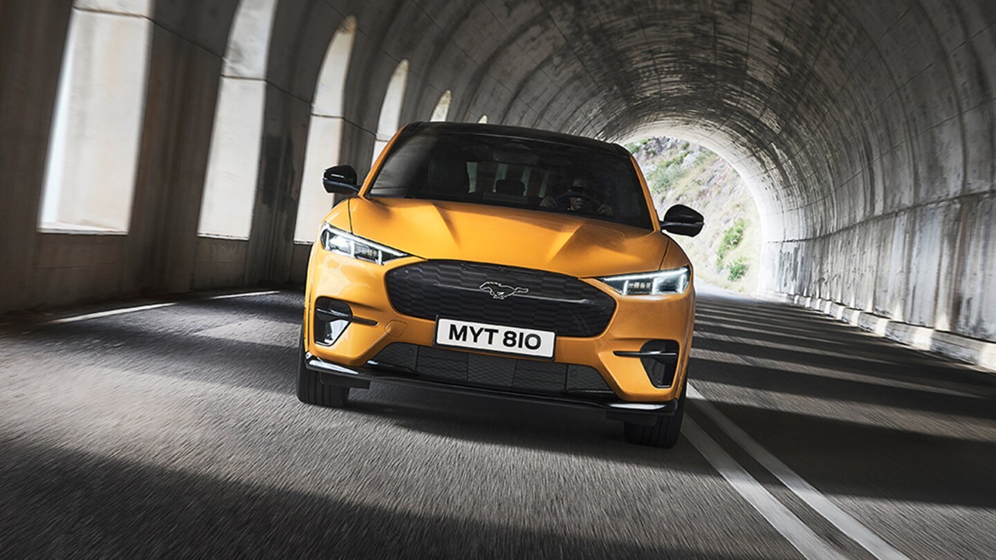 Ford Mustang Mach-E GT in Orange. Frontansicht, durch einen Tunnel fahrend.