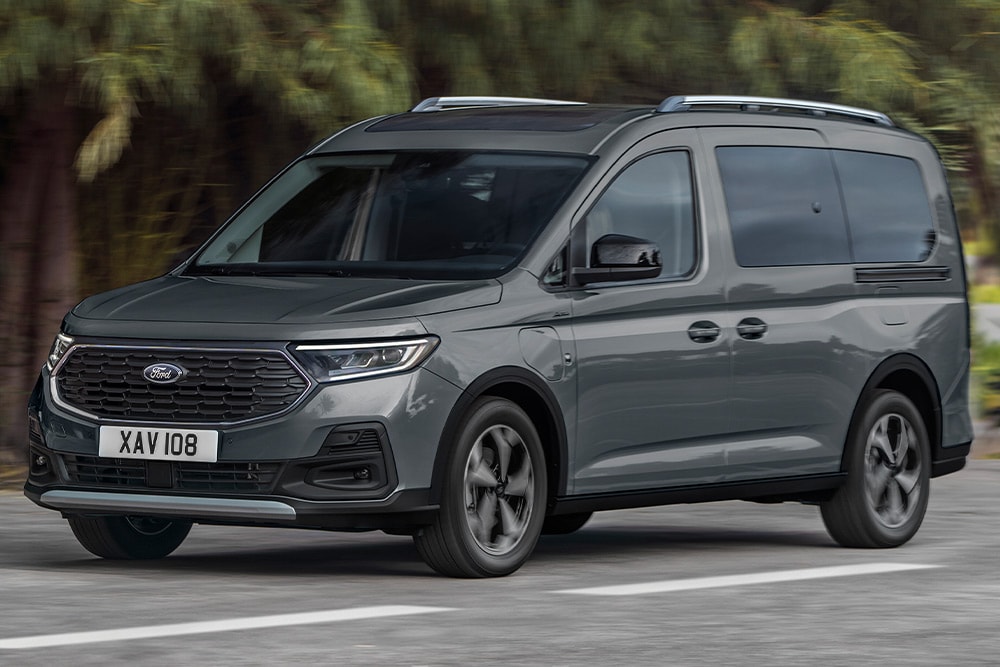 Ford Tourneo Connect in Grau ¾-Frontansicht fährt auf gebirgiger Landstrasse mit Fluss im Hintergrund
